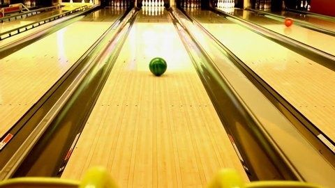Grüne Bowlingkugel rollt mittig über eine glänzende Bowlingbahn